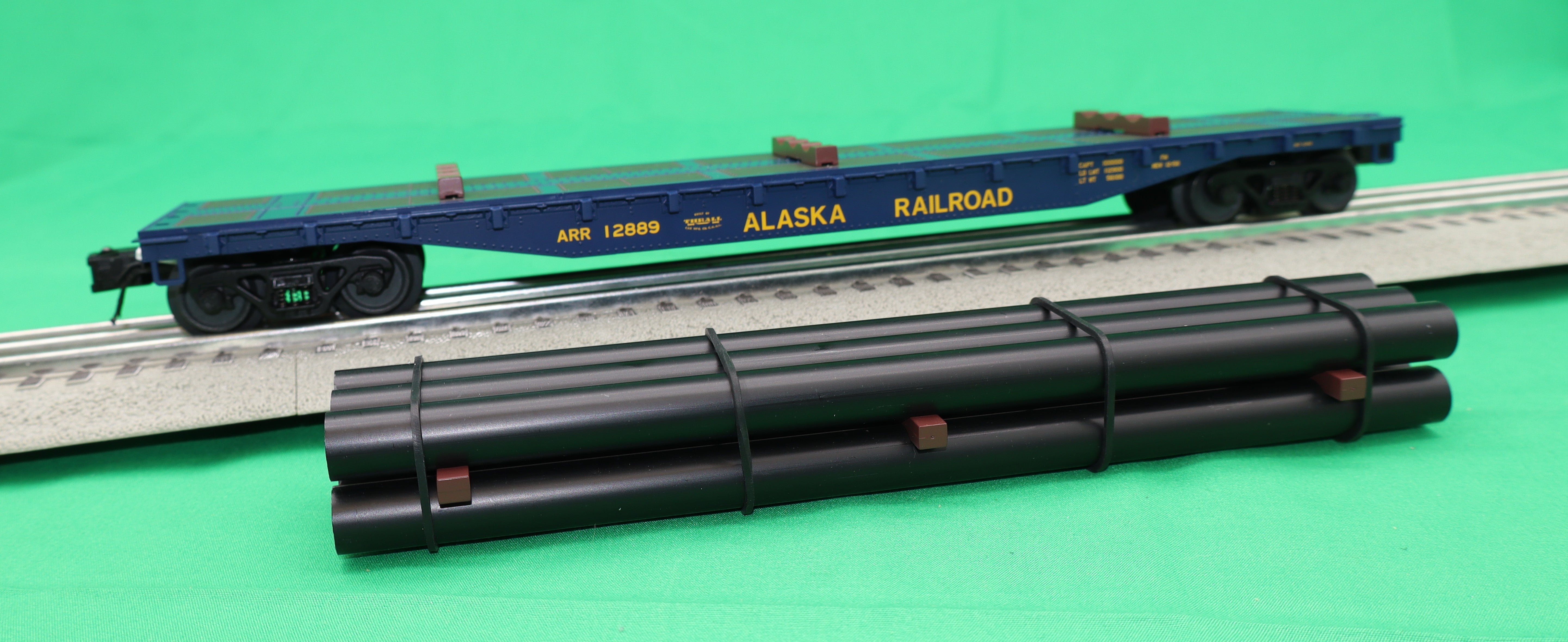 Atlas O 3001880 - Trainman - 52'6" Flat Car "Alaska Railroad" w/ Pipe Load